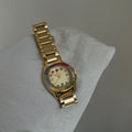 Gold watch with a colorful gemstone bezel on a white surface