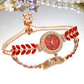 Gold watch with red gemstone leaf shape on a white background