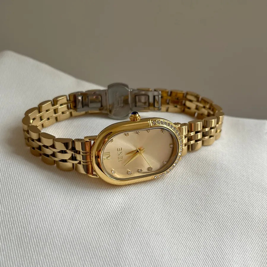 womens slim gold bracelet watch with oval face and beige with diamonds for numbers